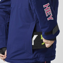 Load image into Gallery viewer, A woman wearing a blue ski jacket with red zip details by Hey Sport, made with ECONYL® regenerated nylon.