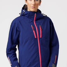 Load image into Gallery viewer, A woman wearing a blue ski jacket with red zip details by Hey Sport, made with ECONYL® regenerated nylon.
