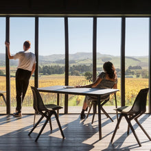 Charger l'image dans la galerie, Two people in their living room admiring the view, with black Noho chairs made with ECONYL® regenerated nylon in the background.
