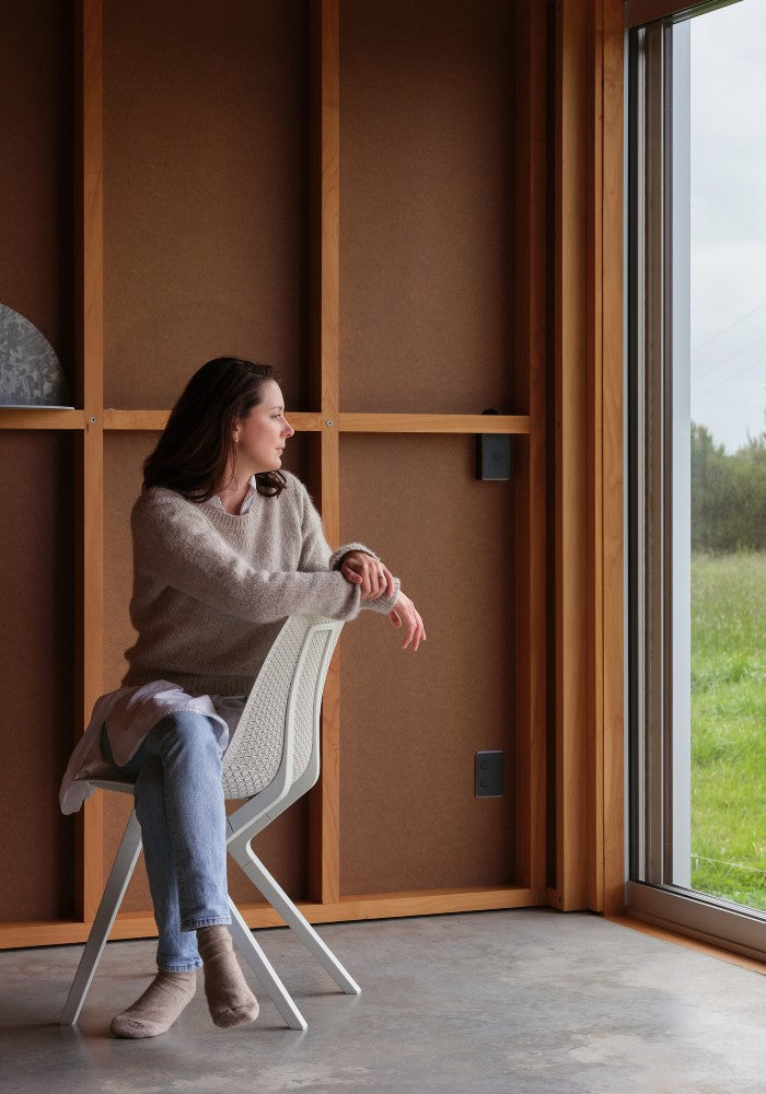 Woman sitting on a white Noho chair made with ECONYL® regenerated nylon.