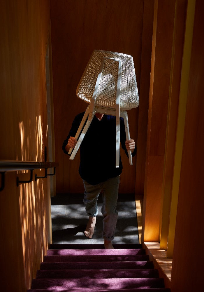 Man holding a white Noho Move chair made with ECONYL® regenerated nylon.