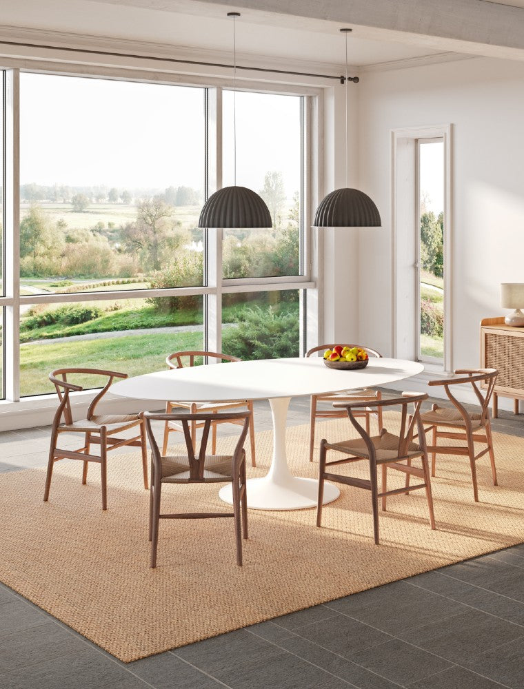 Modern living room with a beige SynSisal weave rug, a white table in the center, a pendant light, ceiling-mounted speaker, and a window overlooking a green field.
