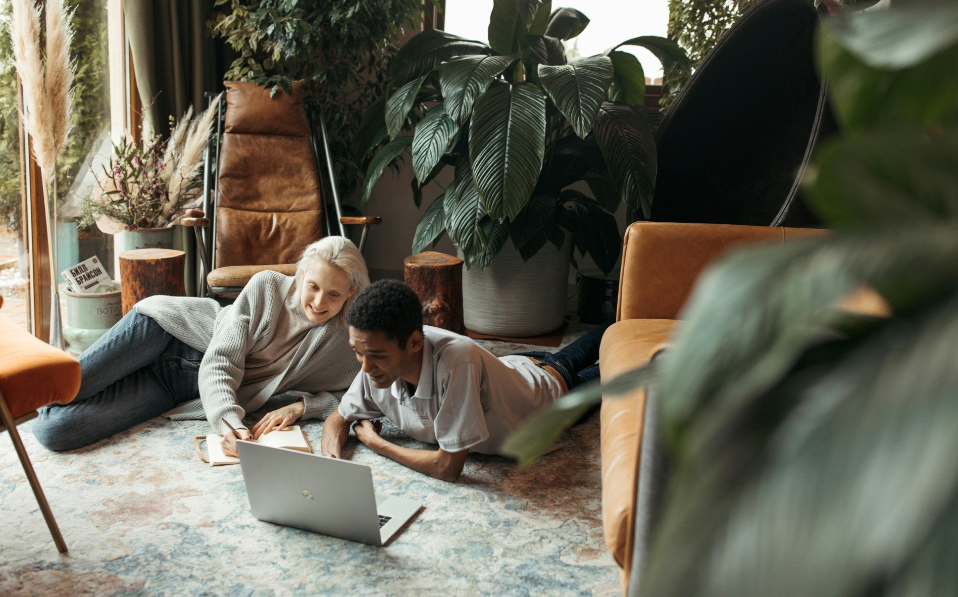 Couple using laptop in a cozy, plant-filled, sustainable living room