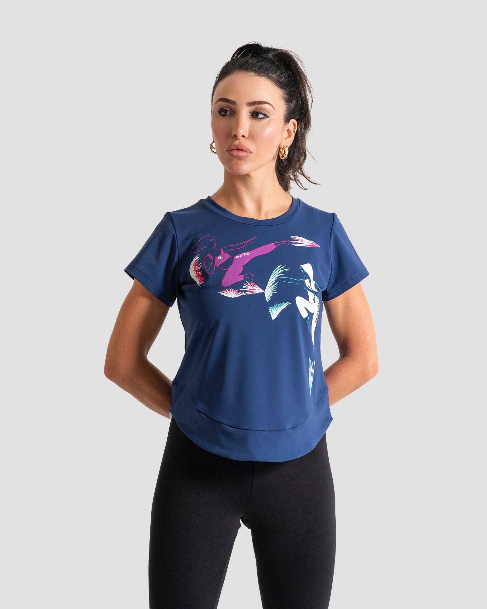 A woman modeling a blue short-sleeve athletic t-shirt with a colorful abstract graphic print on the front, made with ECONYL®nylon, by the brand GoofyPRO