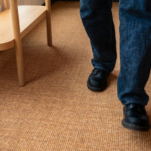 Charger l'image dans la galerie, Person wearing blue jeans and black shoes on a brown carpet. Rug by Synsisal made with ECONYL® regenerated nylon
