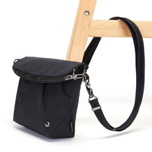 Charger l&#39;image dans la galerie, Side view of the Pacsafe Citysafe CX Anti-Theft Convertible Crossbody color Black made with ECONYL® regenerated nylon locked to a chair
