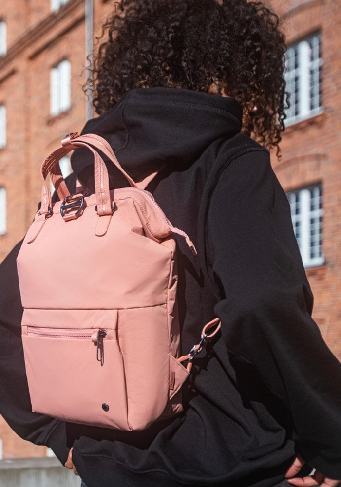 Woman travelling with the Pacsafe Citysafe CX Anti-Theft Mini Backpack color Rose made with ECONYL® regenerated nylon
